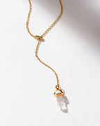 Clear quartz point pendant on a gold lariat chain.