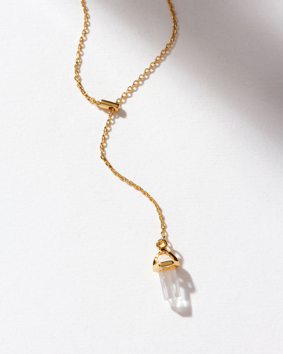 Clear quartz point pendant on a gold lariat chain.