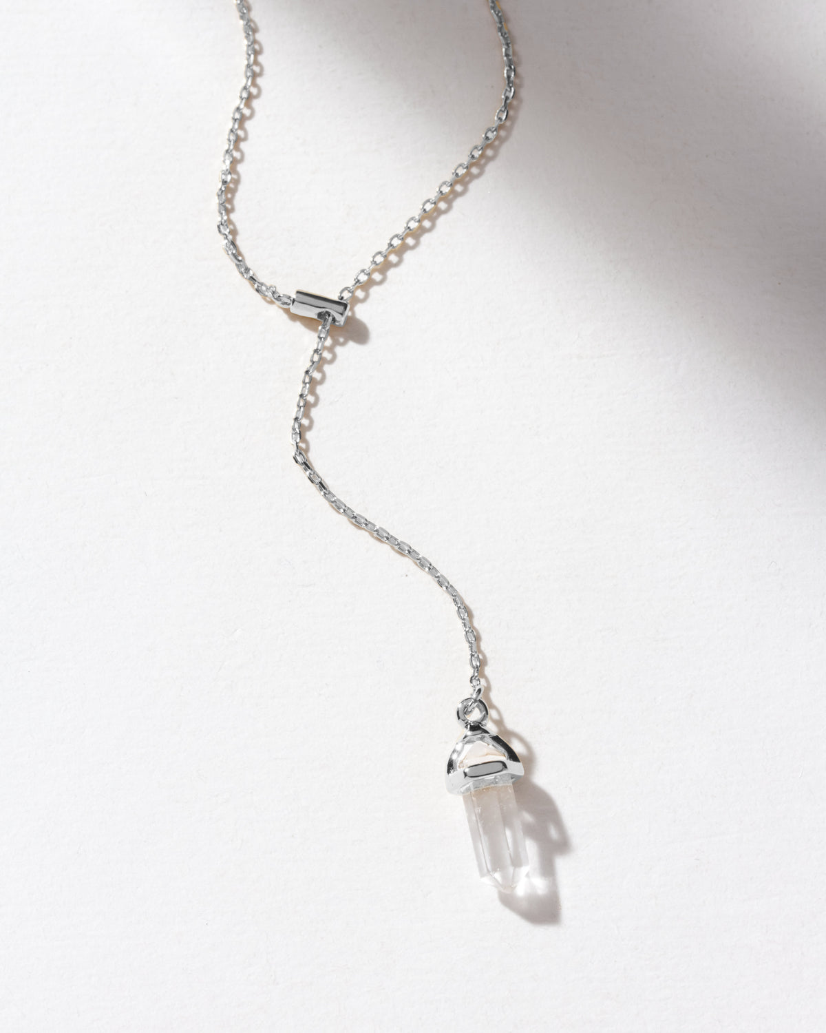 A silver chain necklace with a clear crystal pendant.