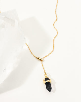 Gold necklace with a black onyx pendant on a white background