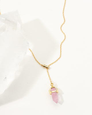 Gold necklace with a pink rose quartz crystal pendant on a white background
