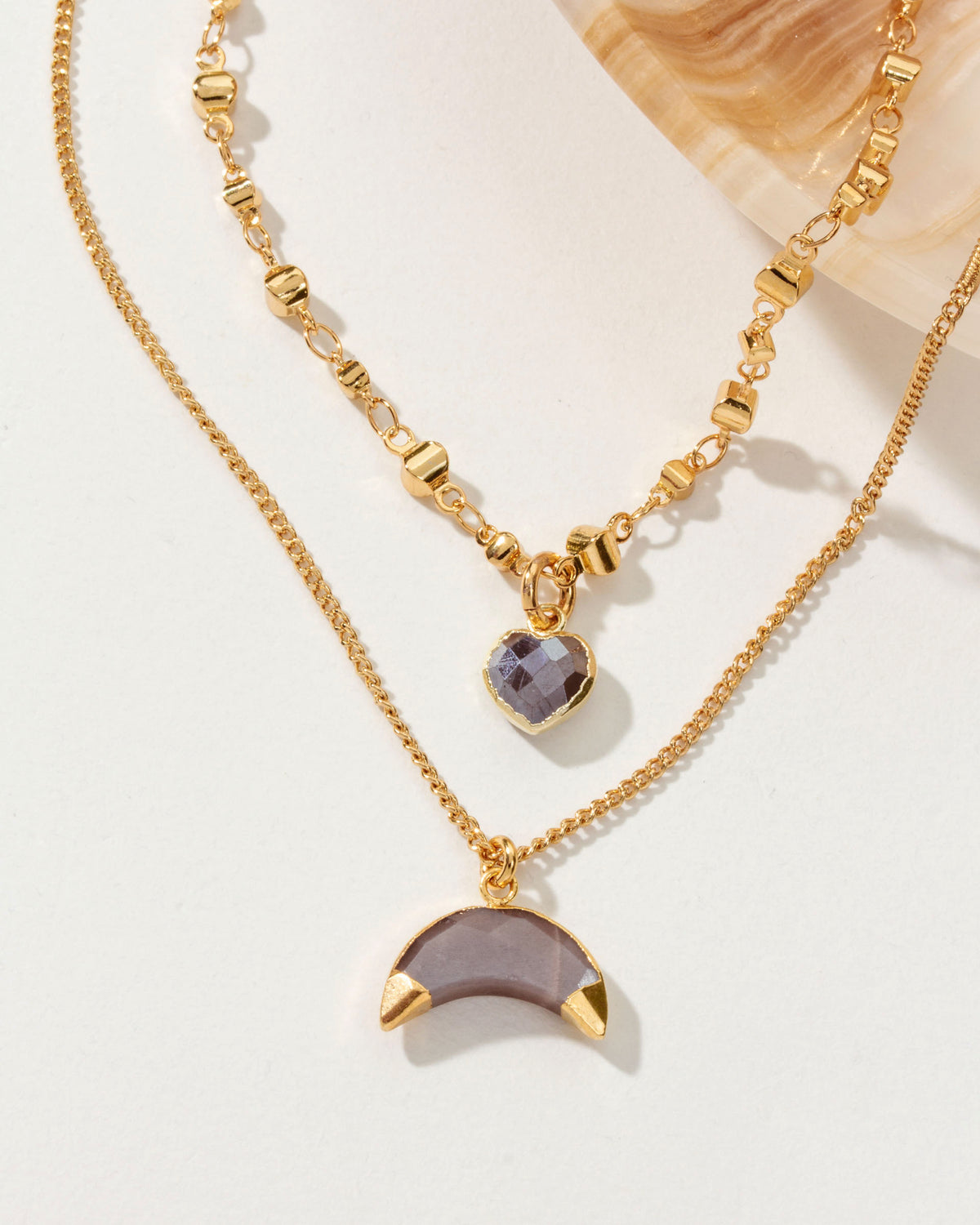 Two-layered gold necklace with a heart and crescent "coffee" moonstone pendant.