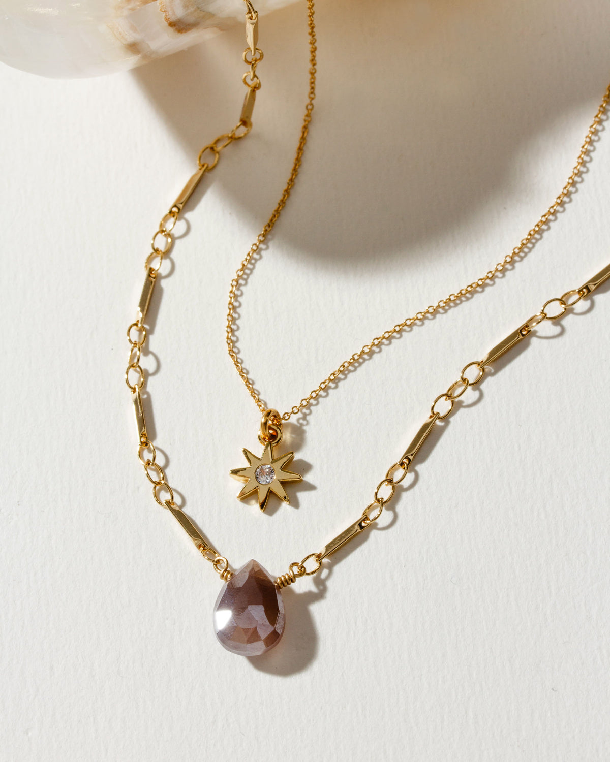 Golden necklace set featuring a teardrop pendant and starburst charm.