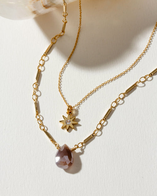 Golden necklace set featuring a teardrop pendant and starburst charm.