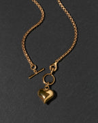 A gold chain toggle front necklace featuring a polished heart-shaped charm.