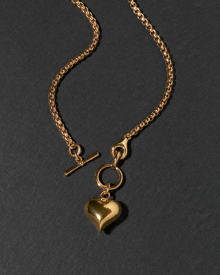A gold chain toggle front necklace featuring a polished heart-shaped charm.