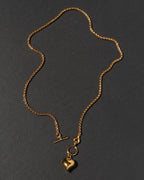 A gold chain necklace with a toggle clasp and a heart-shaped charm.