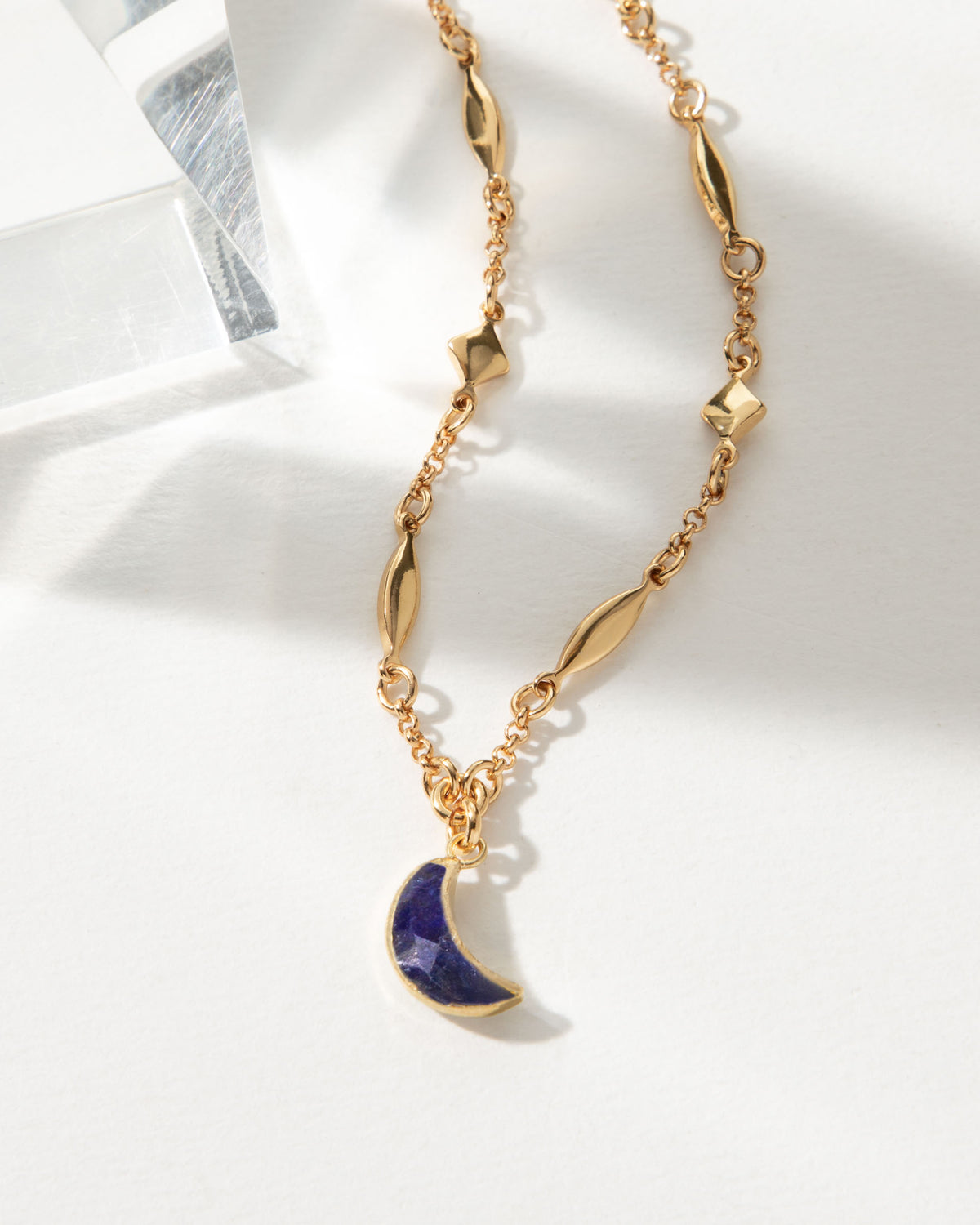 Dolce Luna necklace with a gold chain and sapphire crescent moon pendant.