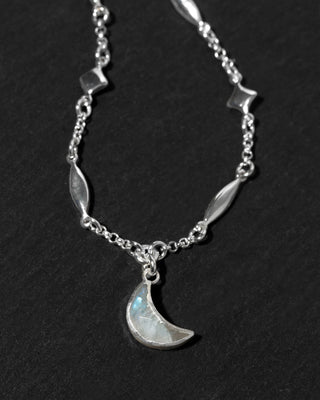 A silver-toned necklace featuring a crescent moon moonstone pendant.