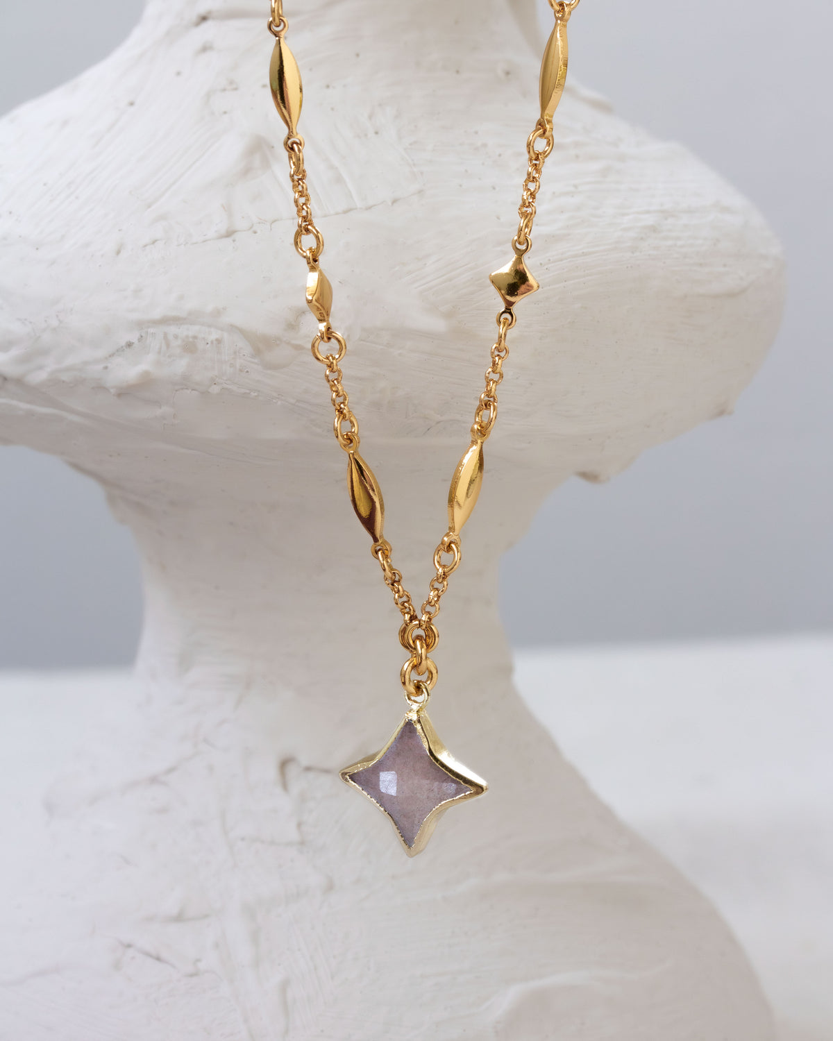 Gold celestial chain necklace with a gemstone Polaris star-shaped pendant.