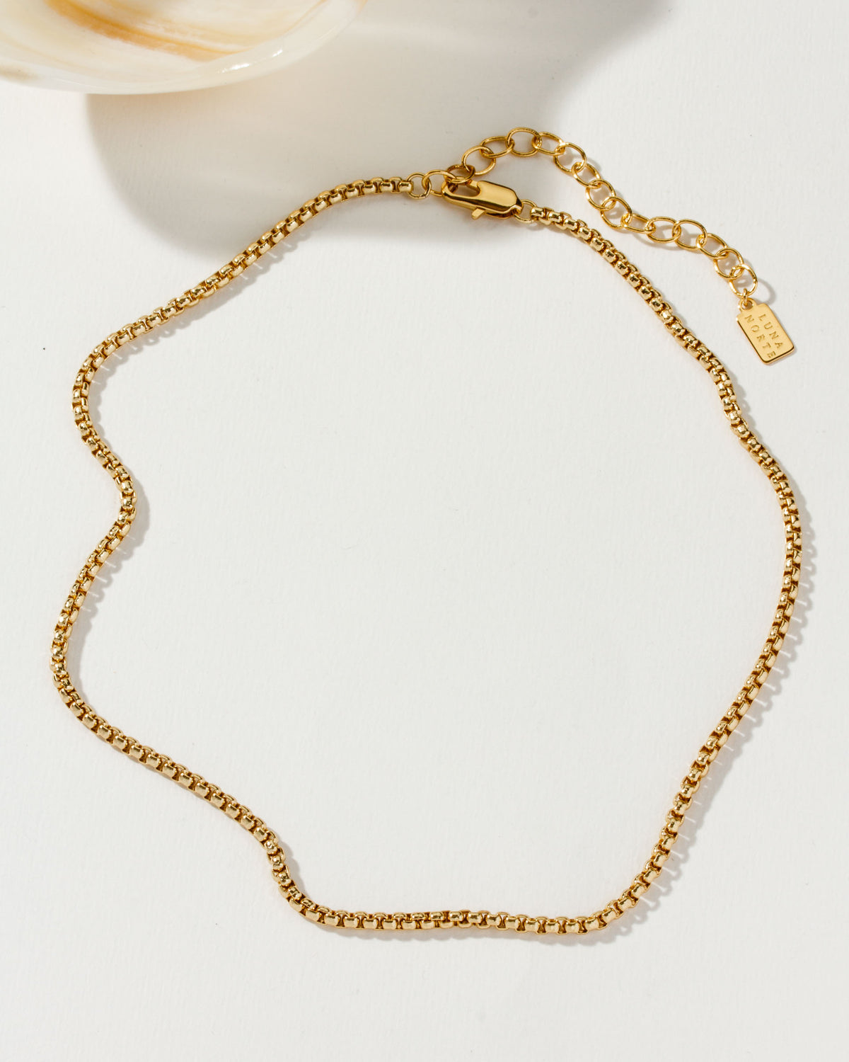 Gold-toned Tubular Popcorn Classic Chain with lobster clasp on a white surface.