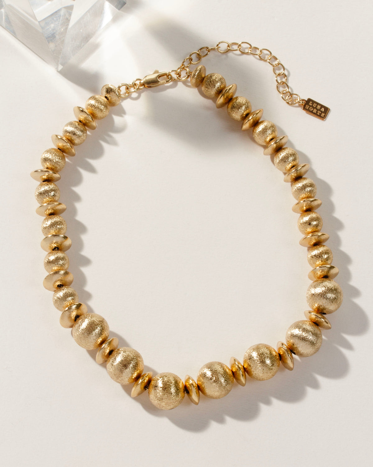 Titan's Gold beaded necklace, with brushed gold textured beads and an adjustable extender chain.