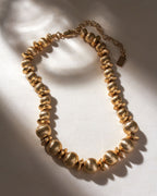 Brushed gold textured necklace with round and disc-shaped beads, and an adjustable extender chain.