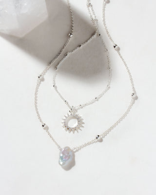 Silver Keshi pearl pendant necklace set with a CZ sun pendant and heart-shaped pearl on a white background