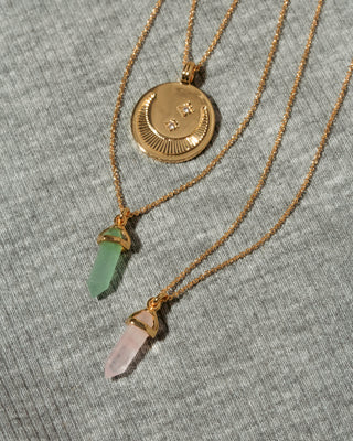 Three gold necklaces the top necklace has a round gold coin shaped pendant with a crescent moon and small clear cz star detail. Bottom necklace has genuine stone prism crystal point  charm.