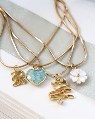 Gold necklaces with various charms on a light fabric background