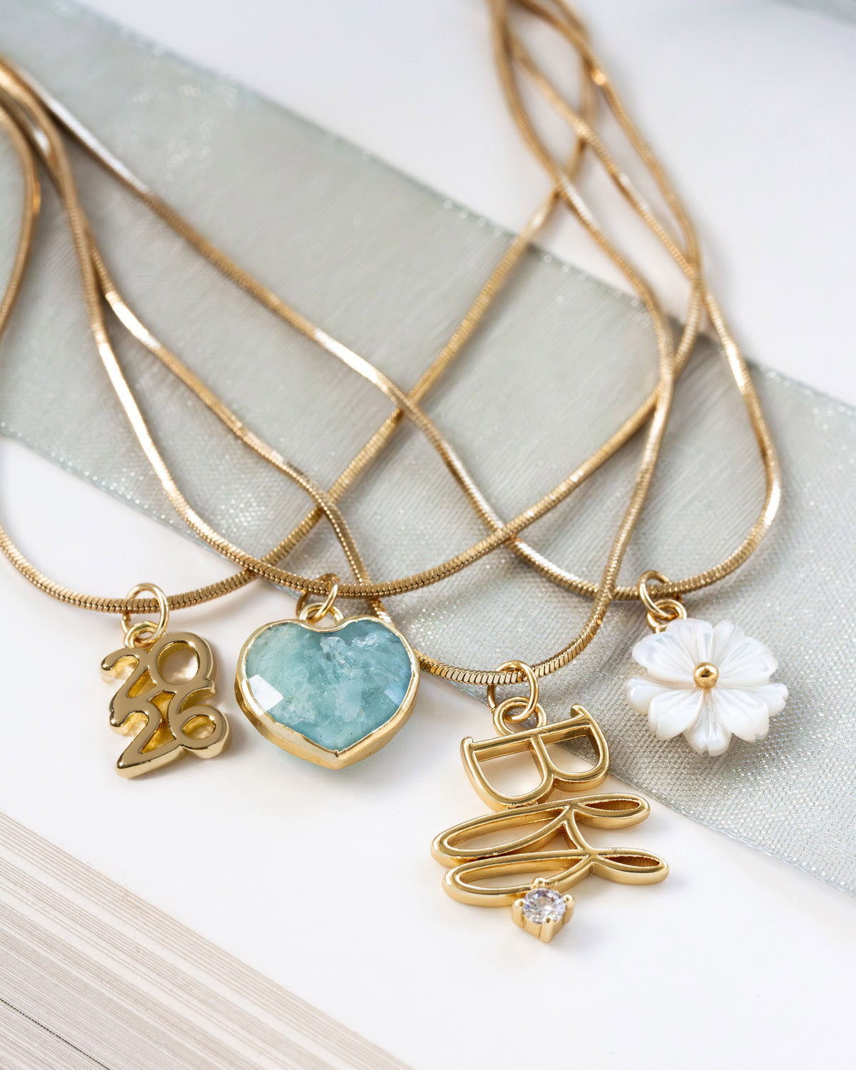 Gold necklaces with various charms on a light fabric background