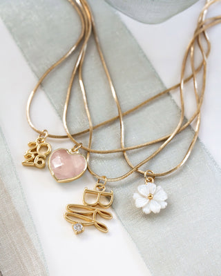 Gold necklaces with various charms on a light fabric background