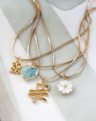 Gold necklaces with various pendants on a light fabric background