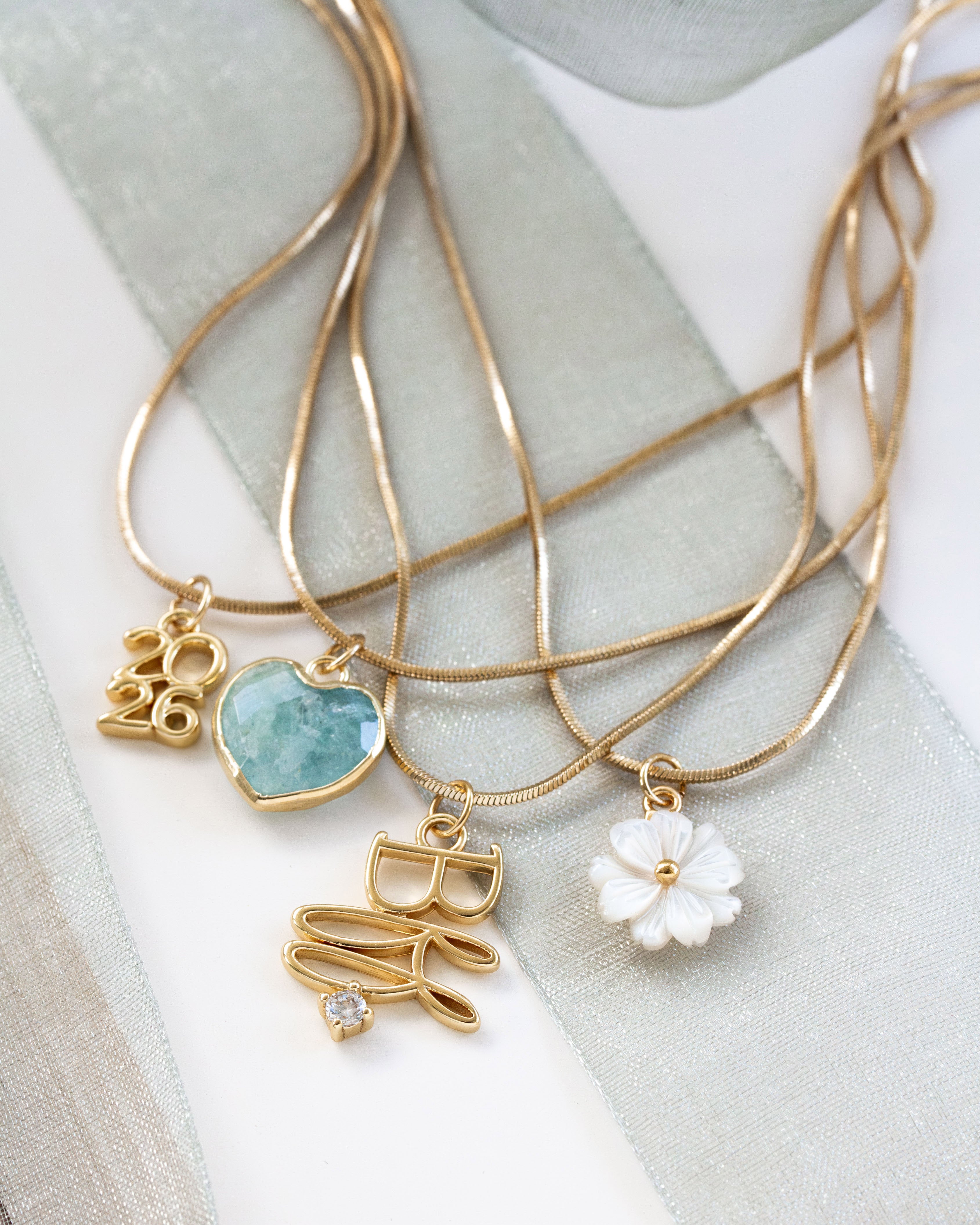 Gold necklaces with various pendants on a light fabric background