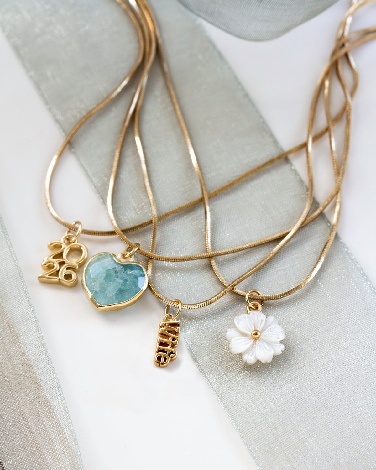 Gold necklaces with "wife" and "2026" and other pendants.