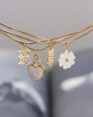 Gold necklaces with various charms on a gray background