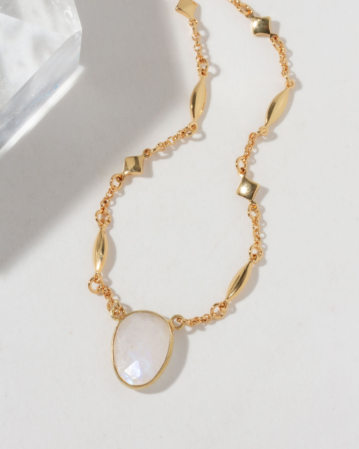 Gold necklace with a large moonstone stone on a light background