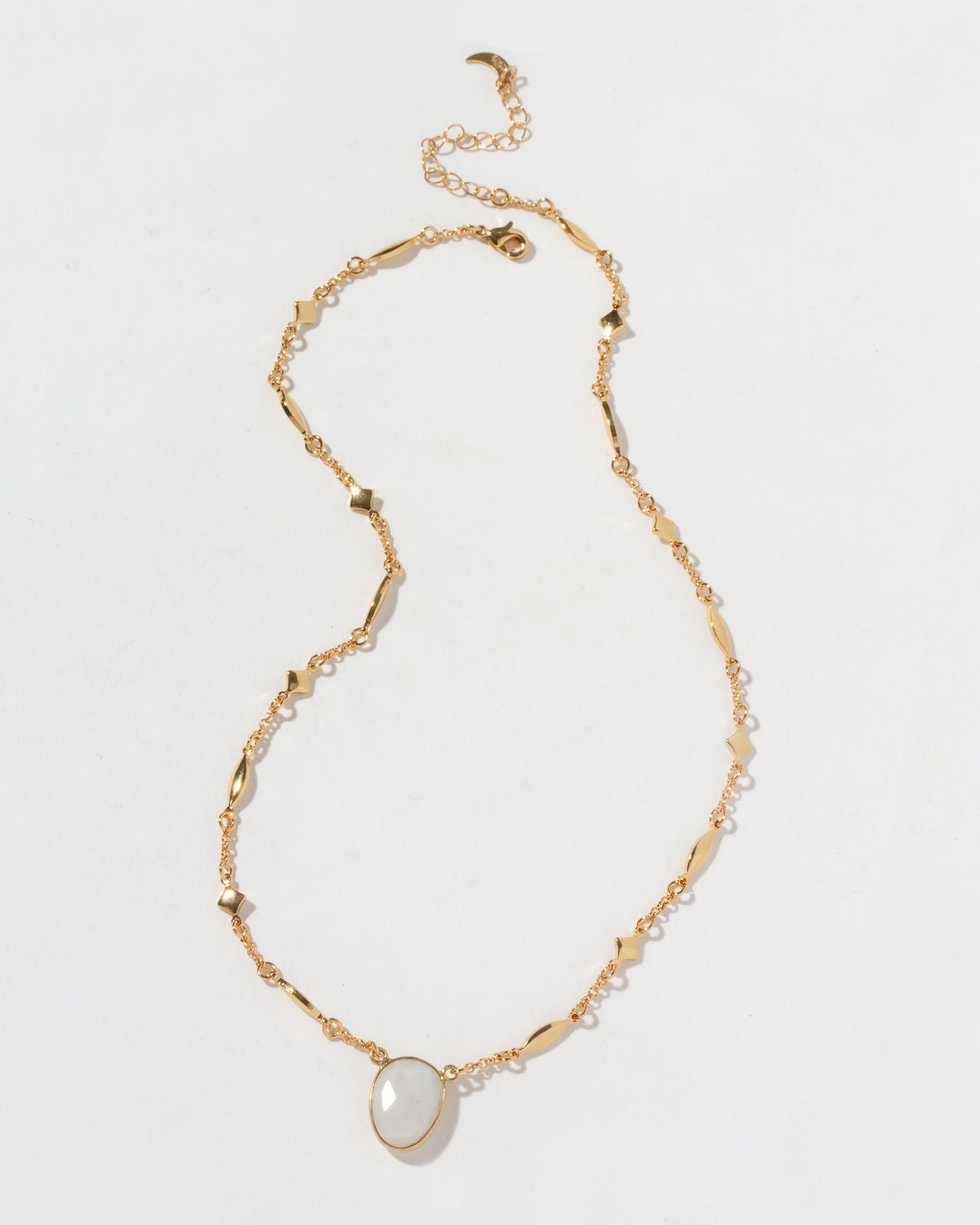 Gold necklace with a moonstone pendant on a light gray background