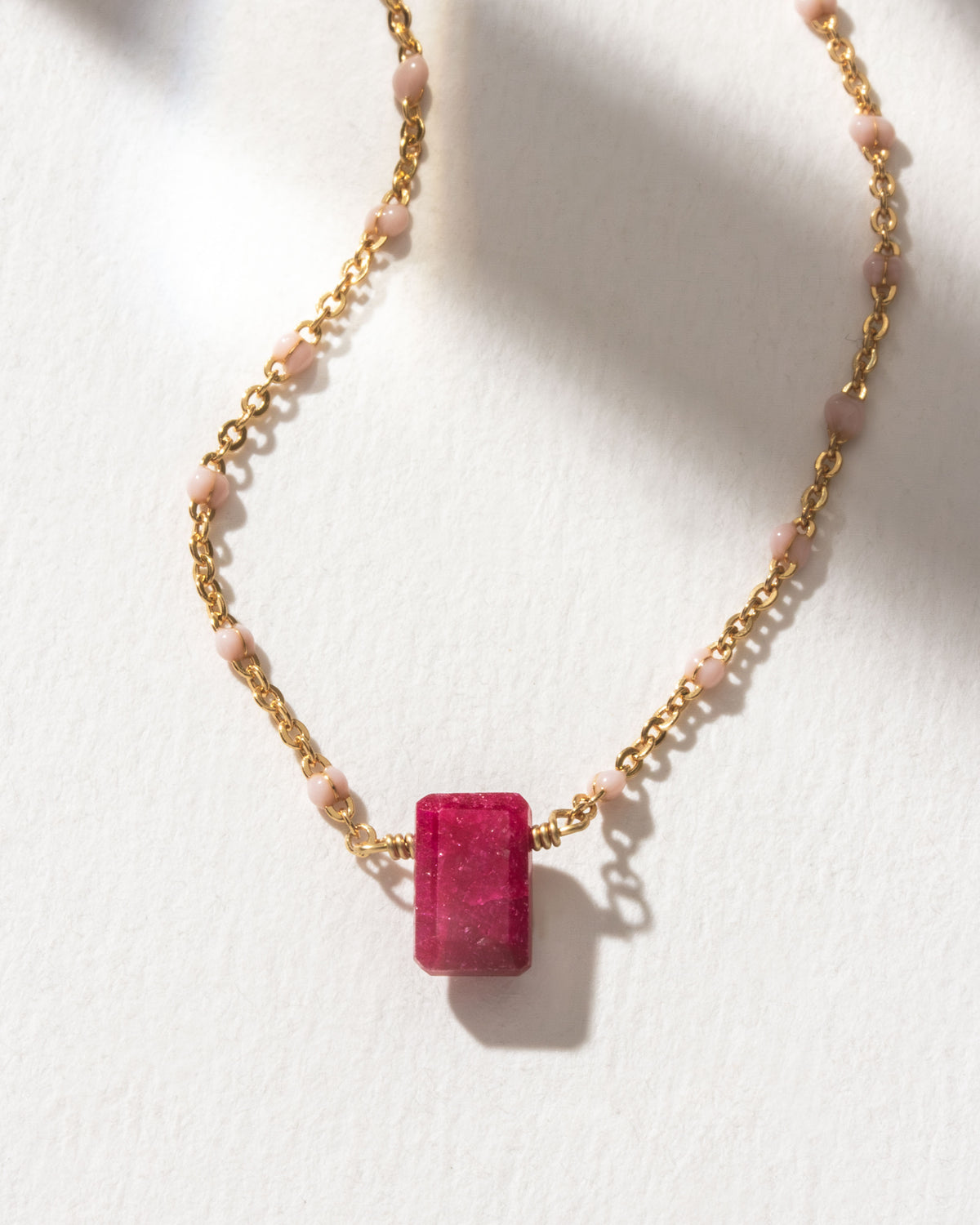 Necklace with a Ruby gemstone pendant and pink beads on a gold chain.
