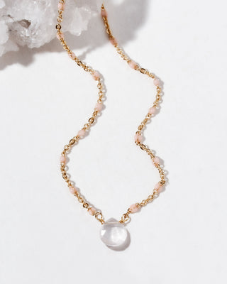 Gold necklaces with pink beads, and large clear teardrop gemstone pendant.