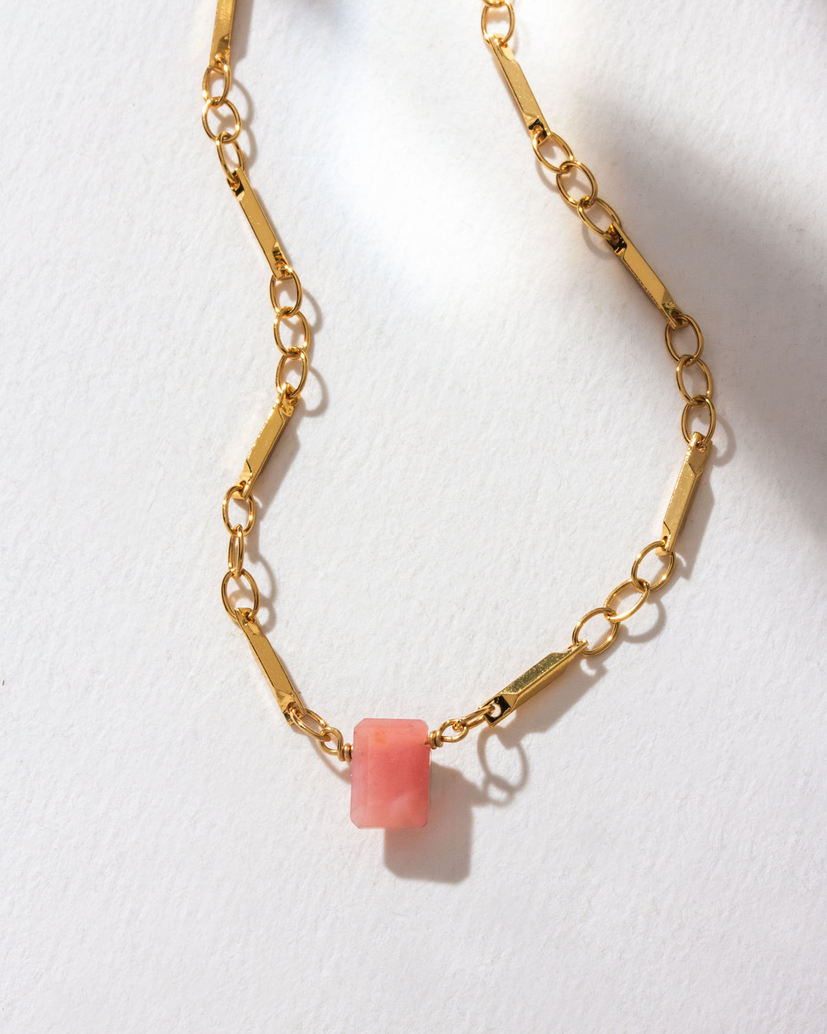 Gold chain necklace featuring a pink opal gemstone pendant.