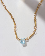 Gold chain necklace with an Aquamarine prism gem pendant.