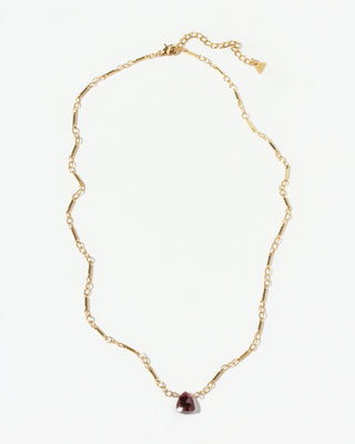 Gold necklace with a triangular red garnet gemstone pendant on a white background