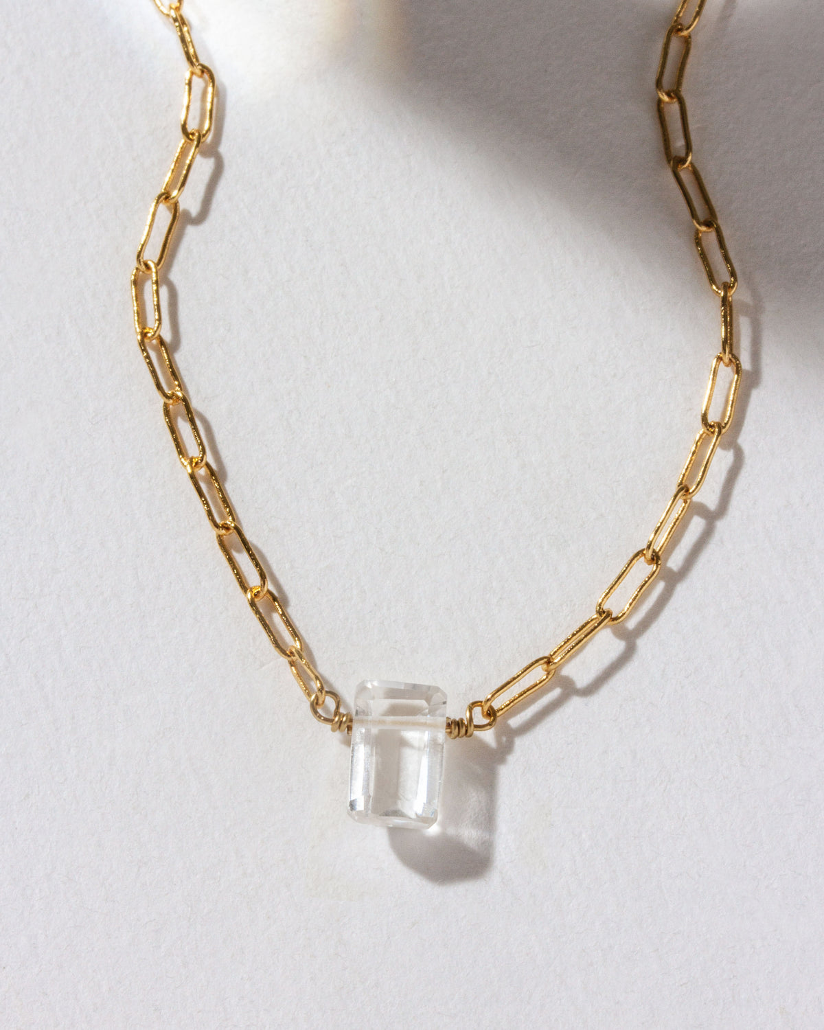 Gold chain necklace with a Clear Quartz gemstone pendant.
