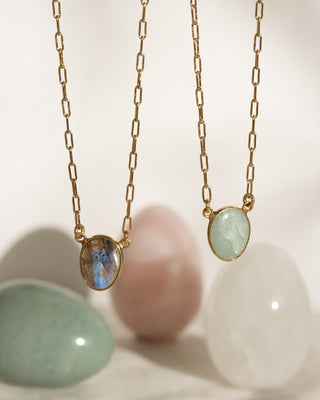 Detail of two gold necklaces, one aquamarine, the other labradorite with out of focus background.
