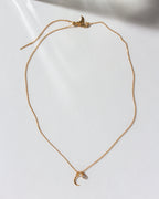 Gold necklace featuring a hammered crescent moon and small CZ charm.