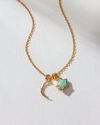 A gold-colored necklace with a crescent moon and amazonite star charm.