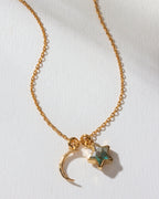 A gold necklace with a hammered crescent charm and a labradorite gem star charm