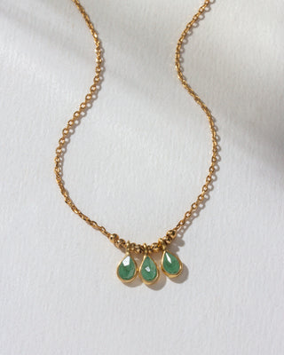 Gold necklace with three green teardrop pendants on a white background