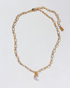 Gold paperclip chain necklace with a mother-of-pearl crescent moon charm and small clear gem.