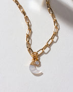 Gold paperclip chain necklace with a mother-of-pearl crescent charm and CZ stone.