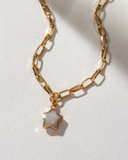 Gold paperclip chain necklace with a moonstone star pendant on a white background.