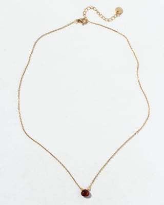 Gold chain necklace with a red garnet gemstone pendant on a white background