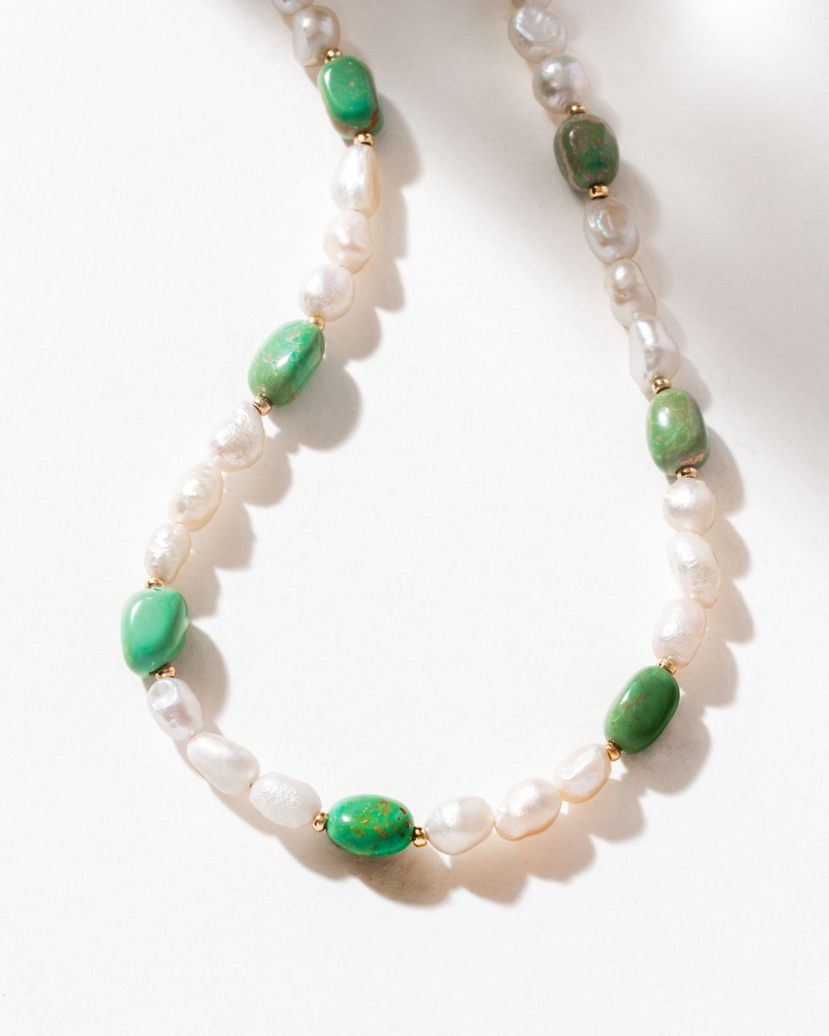 Close-up of a turquoise and pearl beaded necklace.