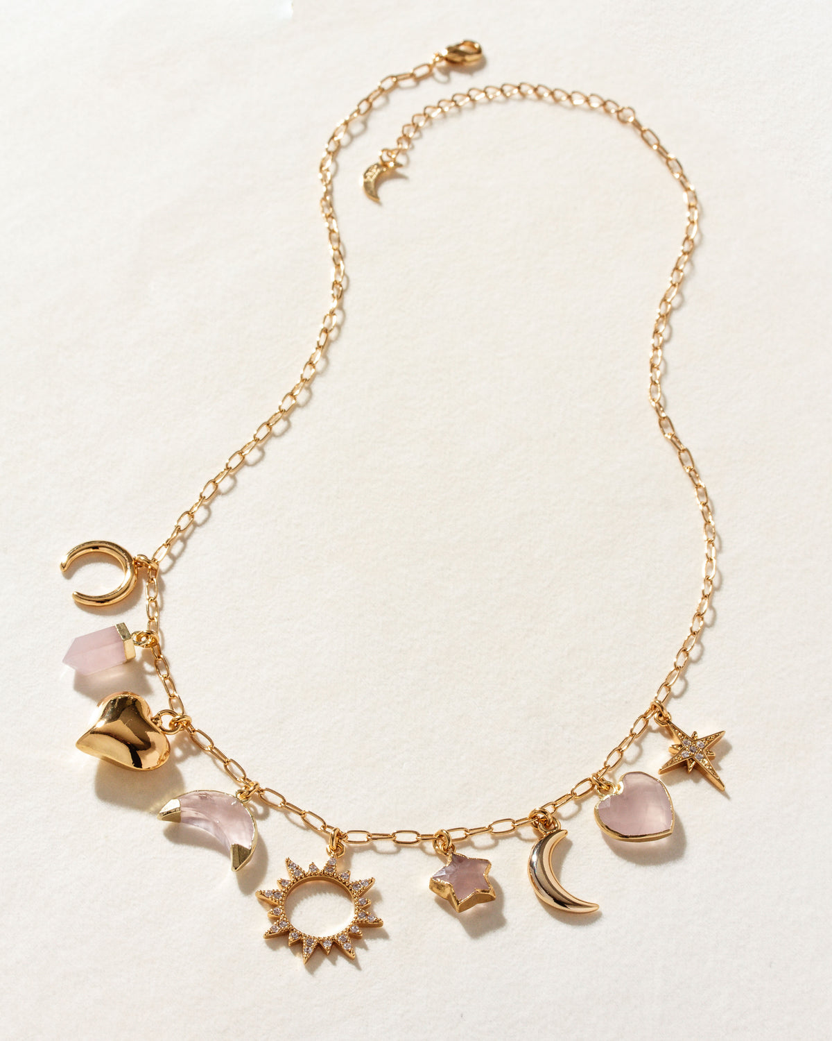 Gold chain necklace with pink rose quartz and gold charms.
