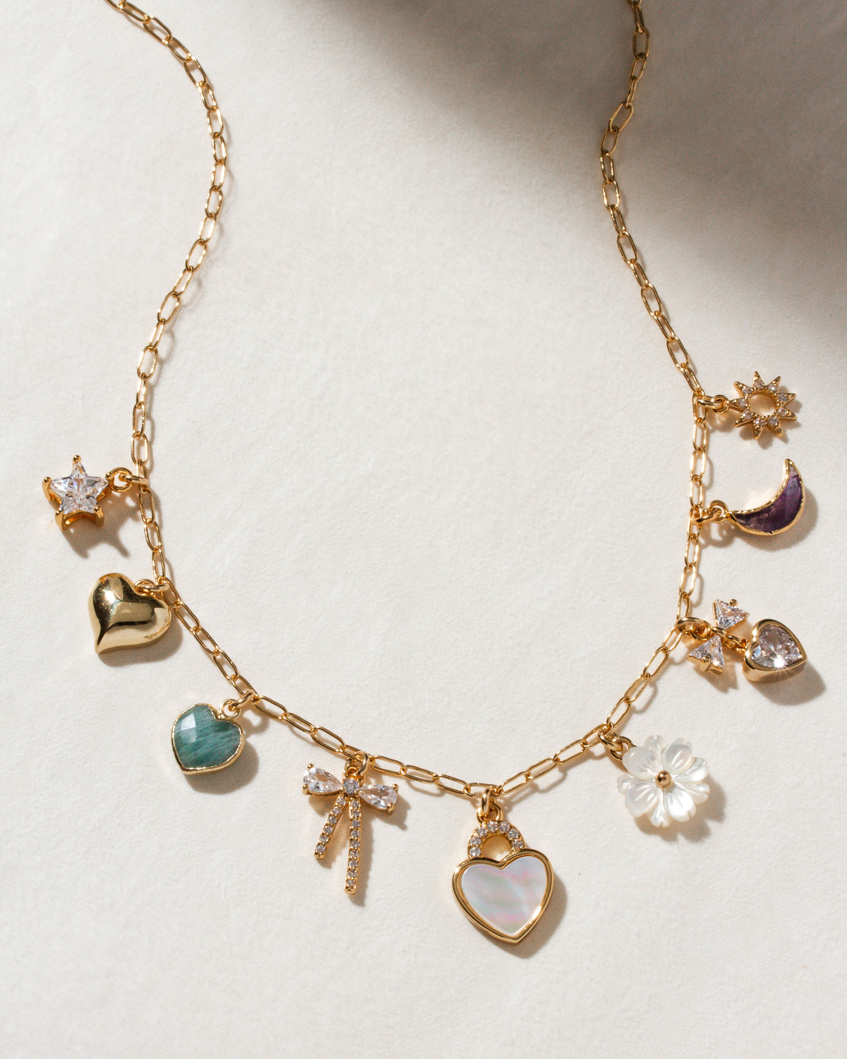 Gold chain necklace with heart, star, moon, bow and flower charms.