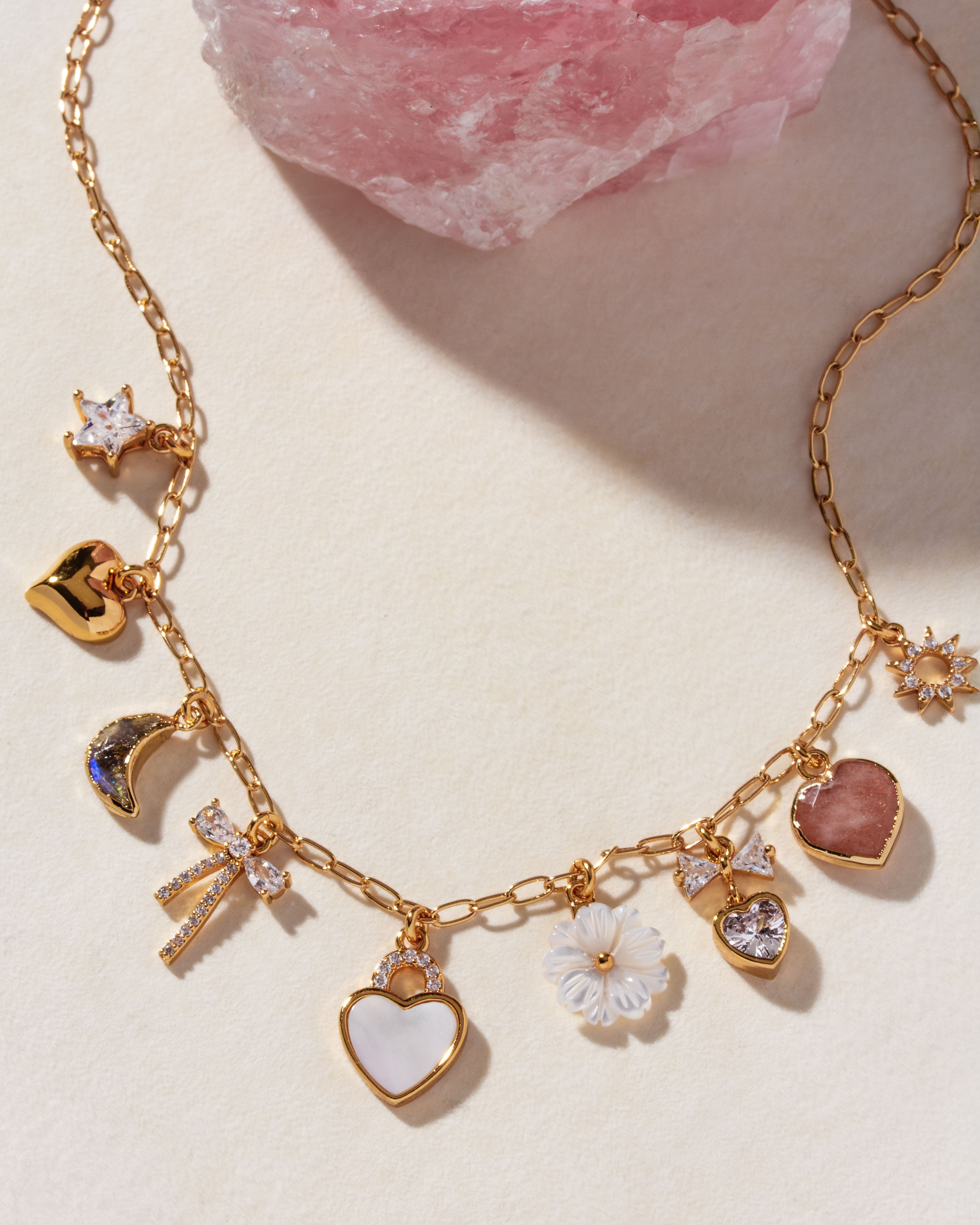 Gold charm necklace with mother-of-pearl heart, labradorite moon, and floral charms