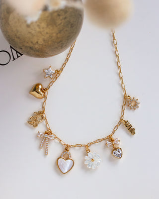 Gold necklace with various charms on a white surface