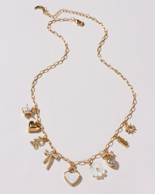 Gold necklace with various charms on a light gray background