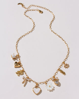 Gold necklace with various charms on a light gray background